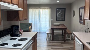 Una cucina con mobili in legno, un forno, una macchina da caffè e un'area pranzo con tavolo e sedie.