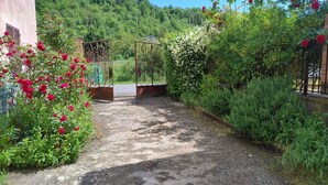 A garden pathway with a gazebo, surrounded by lush greenery and flowering plants. - Cottage Wisterya in Piemonte with pool (Piemonte)