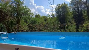 A swimming pool with a ladder, surrounded by trees and a clear sky. - Cottage Wisterya in Piemonte with pool (Piemonte)