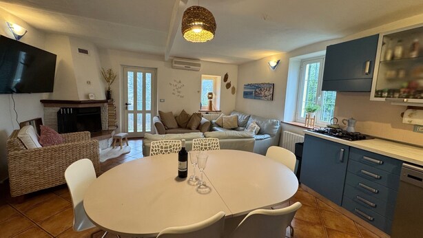 A modern kitchen with a dining area, a fireplace, and a television. - Cottage Wisterya in Piemonte with pool (Piemonte)