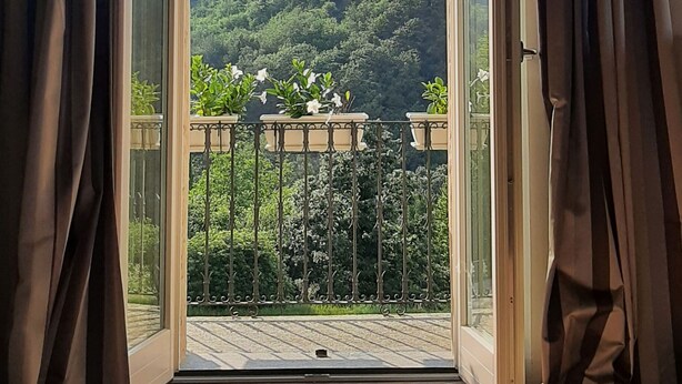A room with a large sliding glass door leading to a balcony with a view of a forested hillside. - Villa Pietra with pool on the Piemonte Hills (Piemonte)