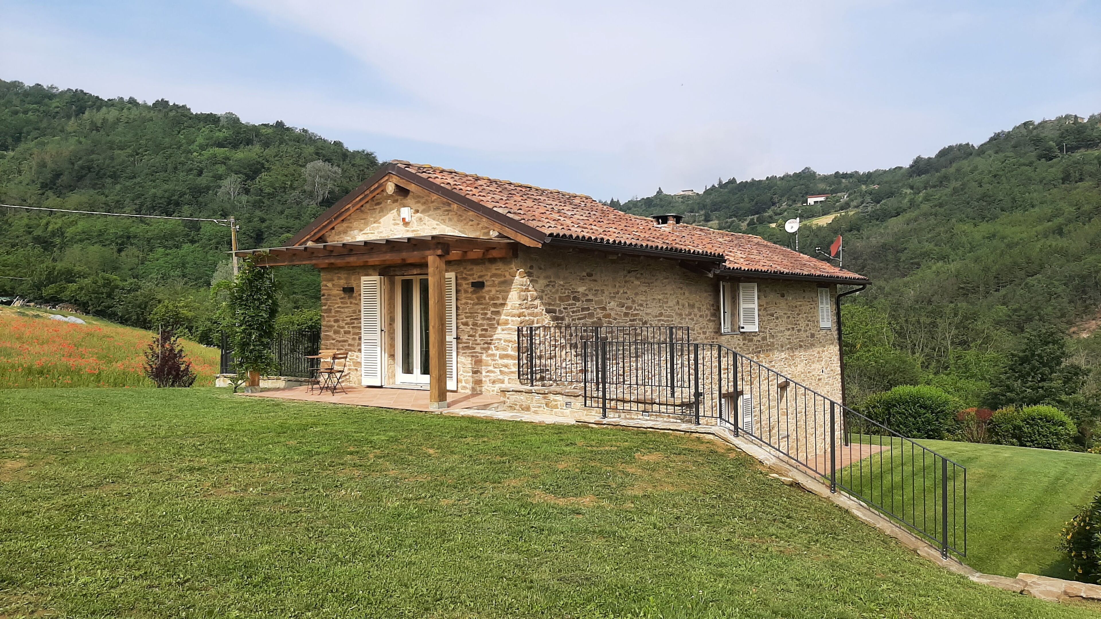 Une maison en pierre avec un toit en tuiles, un petit porche et un jardin clos.