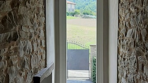 A narrow stairway leading to a window with a view of a fenced field and distant hills. - Villa Pietra with pool on the Piemonte Hills (Piemonte)