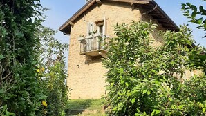 A stone building with a balcony, surrounded by greenery and a stone pathway leading to it. - Villa Pietra with pool on the Piemonte Hills (Piemonte)