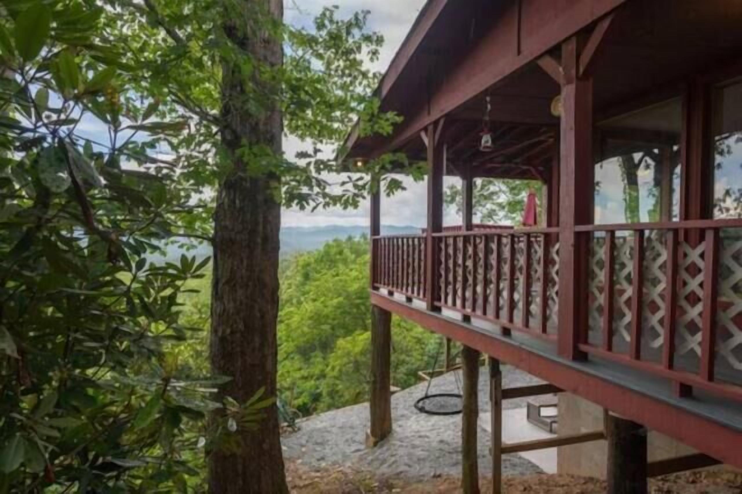 A wooden structure with a balcony overlooking a forested area.