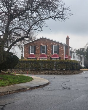 A brick building with a red roof, a chimney, and a gated entrance.