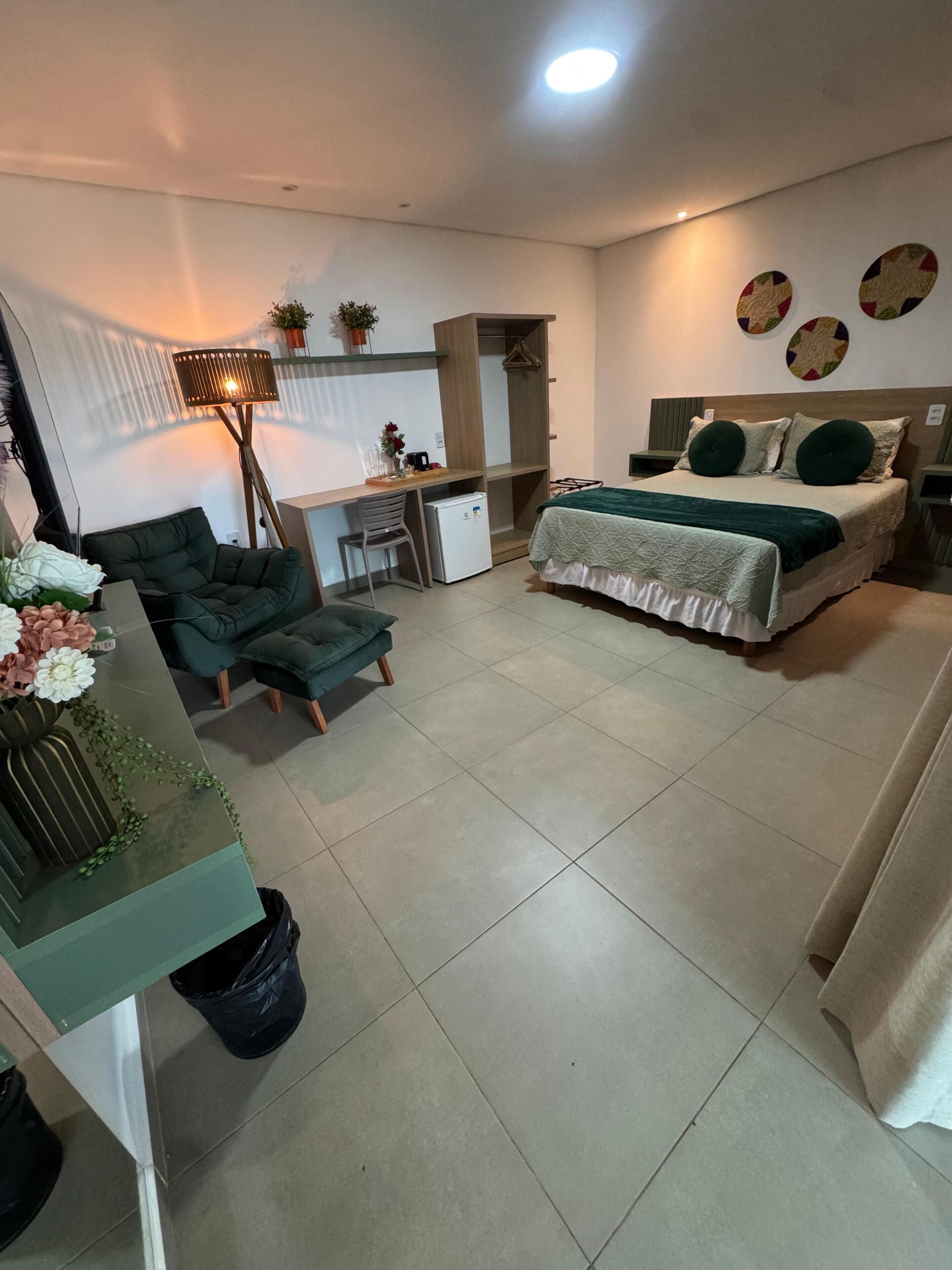 Un dormitorio moderno con cama, escritorio, silla y un refrigerador pequeño.