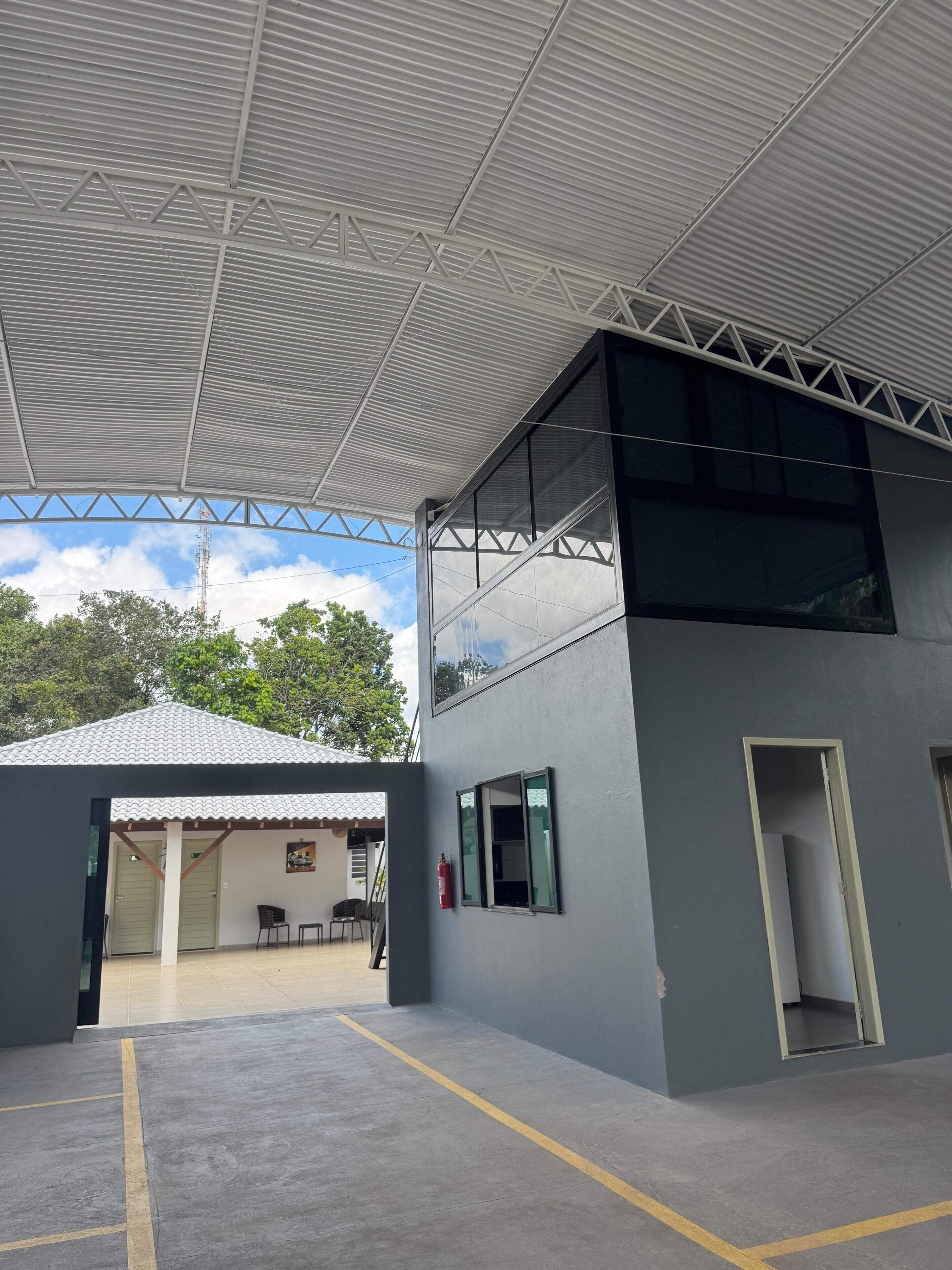 Um edifício com telhado plano, grandes janelas e uma área externa coberta.