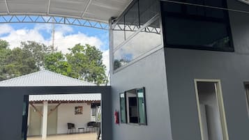 Um edifício com telhado plano, grandes janelas e uma área externa coberta.