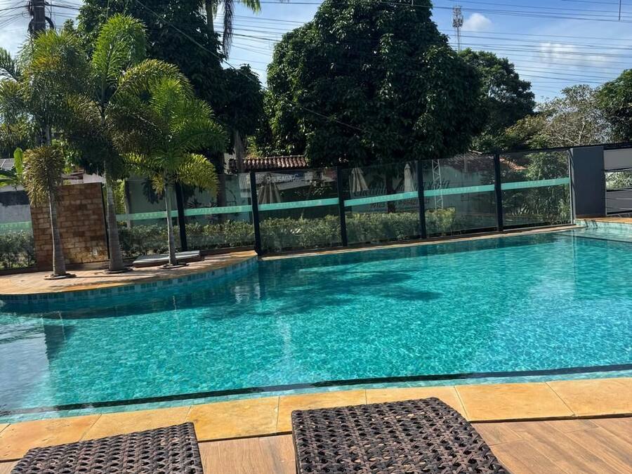 Una piscina con agua cristalina, rodeada de palmeras y una cerca.