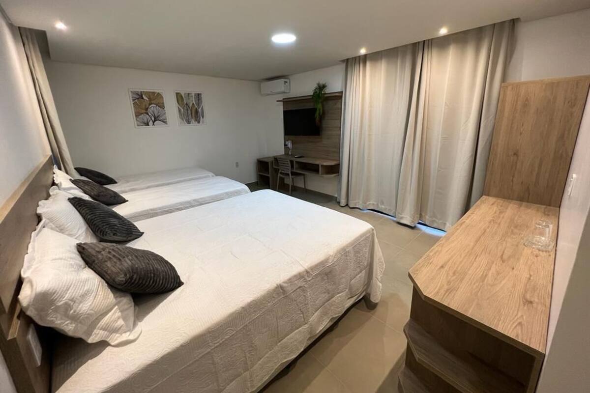 Ein Hotelzimmer mit einem großen Bett, einem Nachttisch aus Holz, einem Schreibtisch und einem Fernseher.