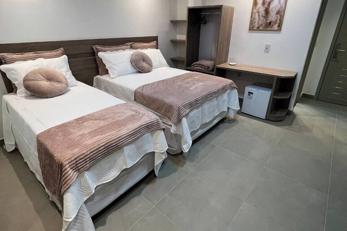 Ein modernes Schlafzimmer mit zwei Betten, einem Kleiderschrank und einem kleinen Schreibtisch.