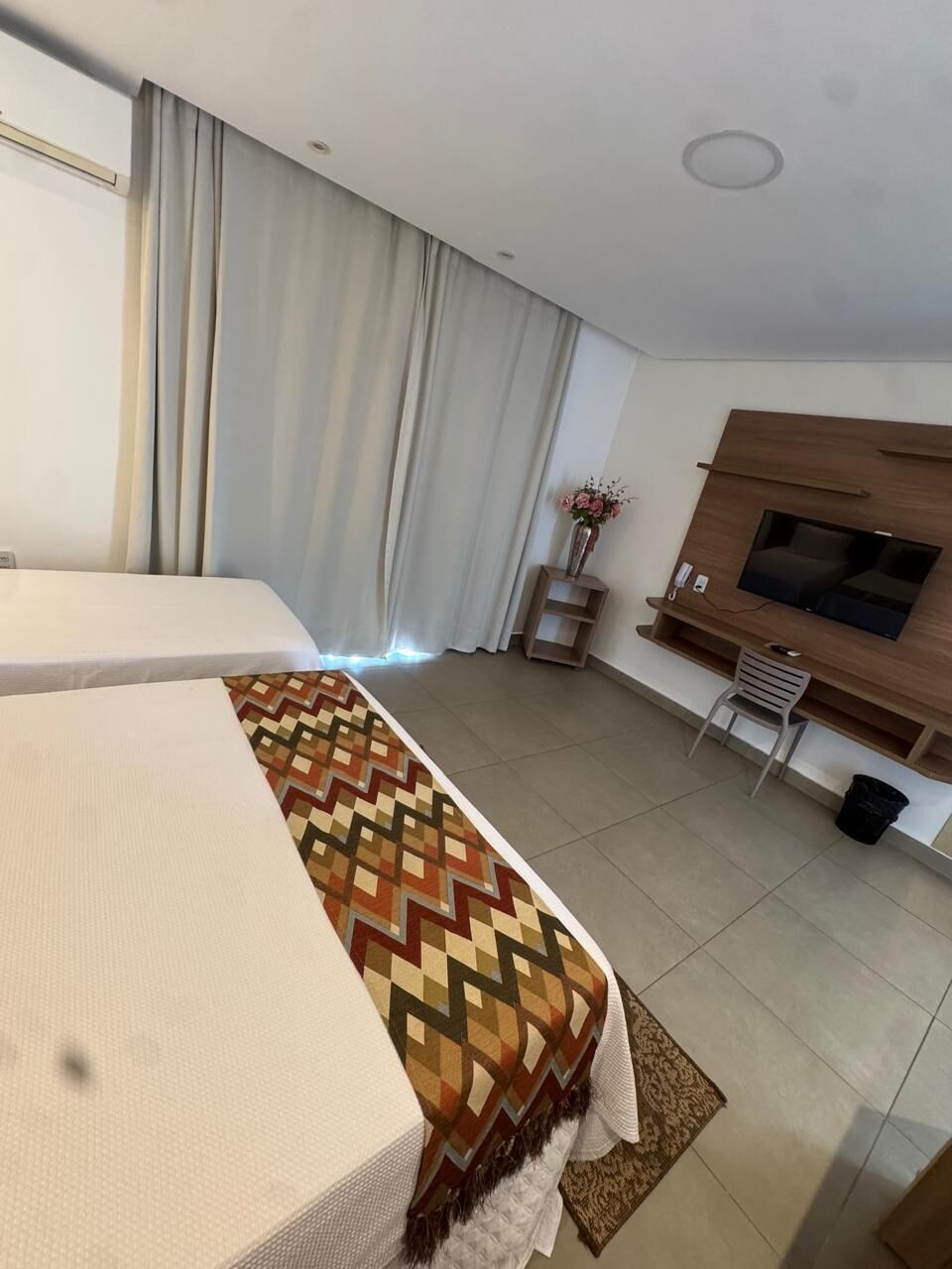 A hotel room with a bed, a TV, a desk, and a chair.
