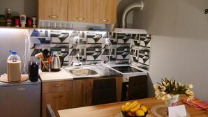 A compact kitchen with wooden cabinets, a stainless steel sink, and a patterned backsplash.
