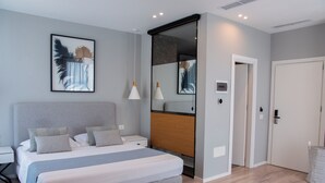 A modern bedroom with a large bed, bedside tables, a mirror, and a door. - Dukes Albania (Orikum)