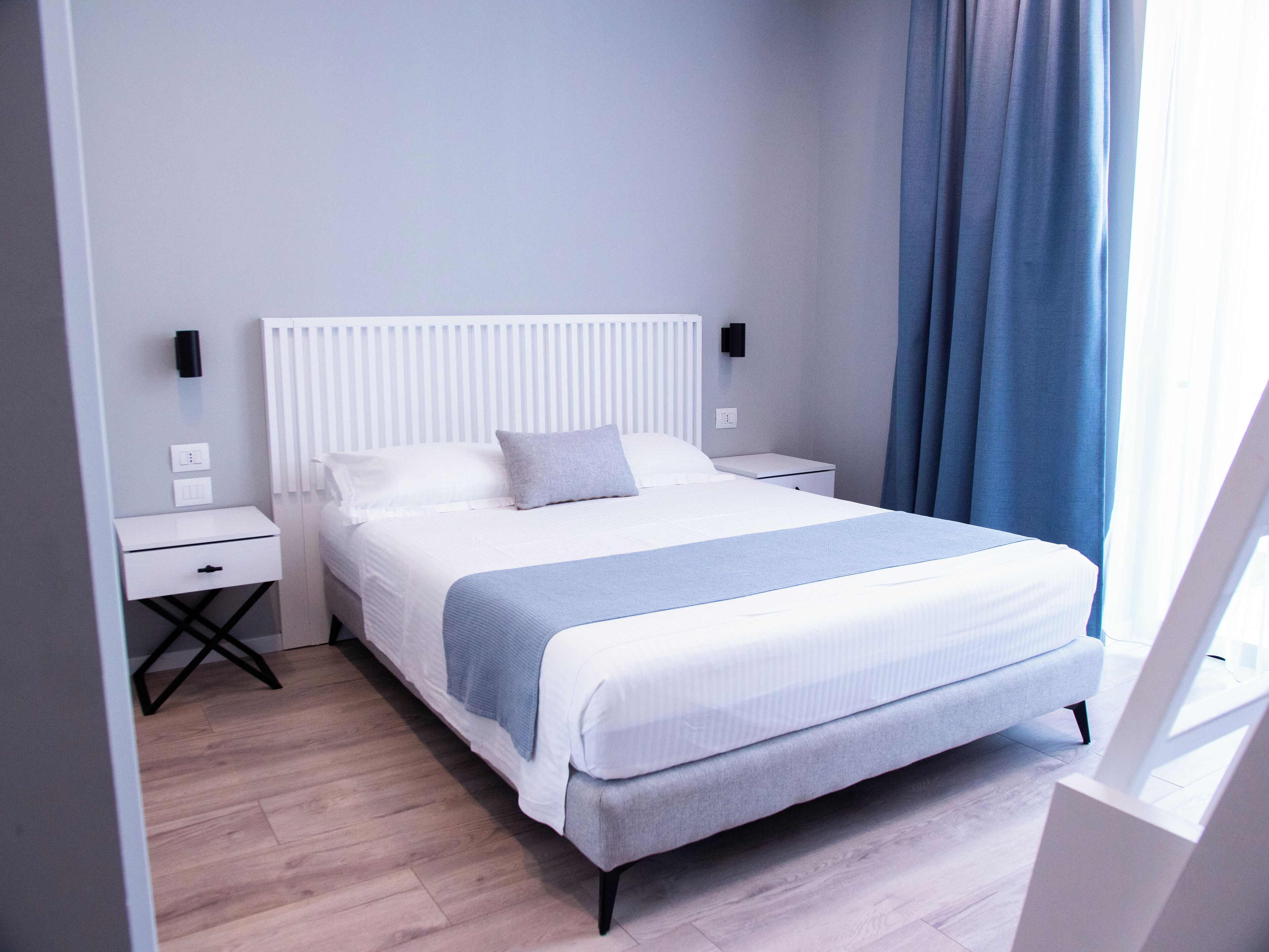 A neatly arranged hotel room with a bed, bedside tables, and a nightstand.