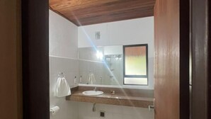 Une salle de bain avec un plafond en bois, un lavabo, des toilettes et un miroir.