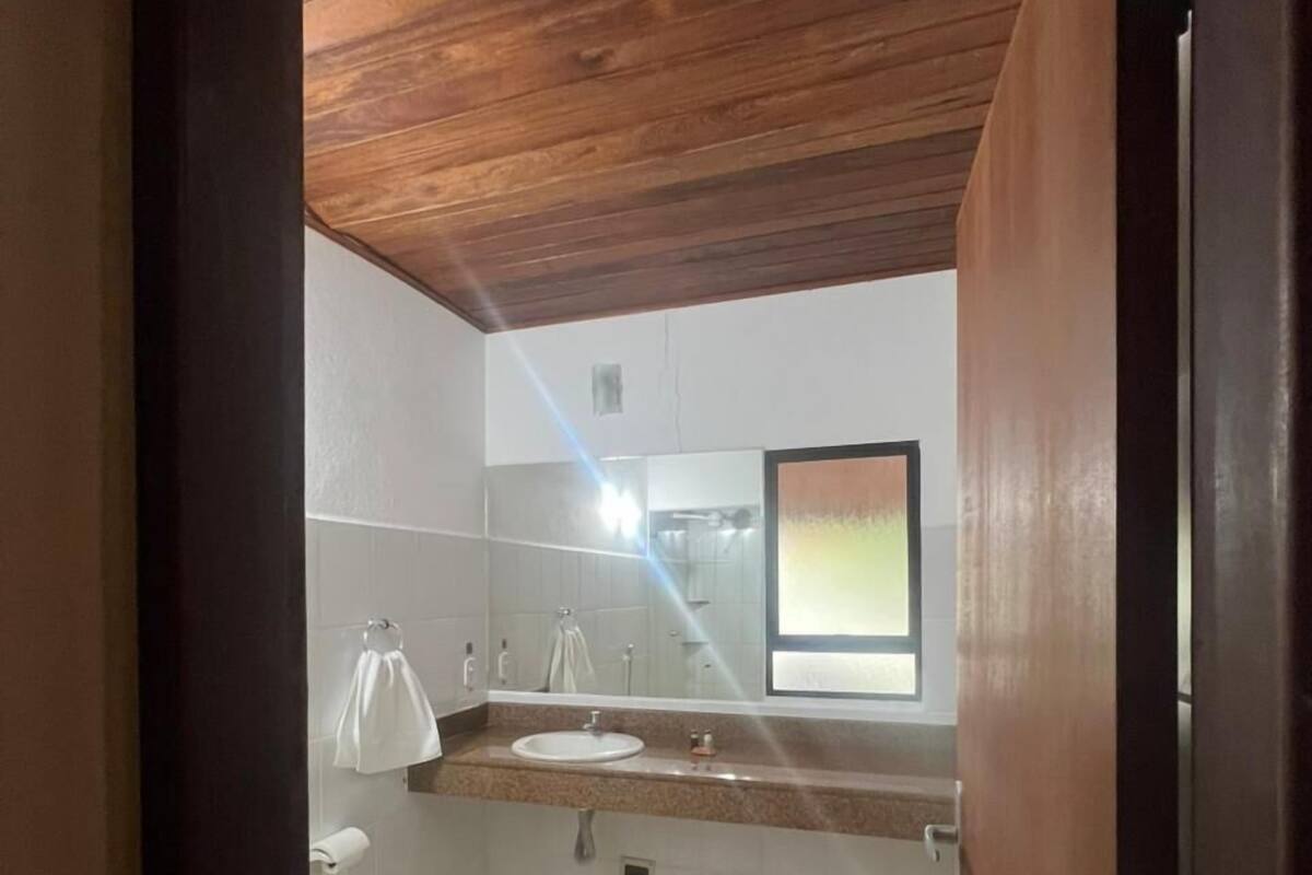 Ein Badezimmer mit Holzboden, einem Waschbecken, einer Toilette und einem Spiegel.