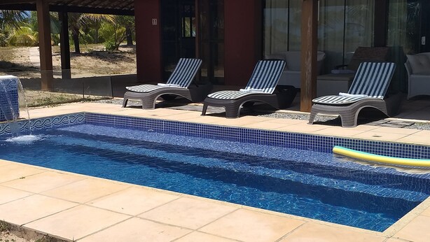 Une piscine dont les bords sont recouverts de carreaux, avec des chaises longues et un petit flotteur gonflable.