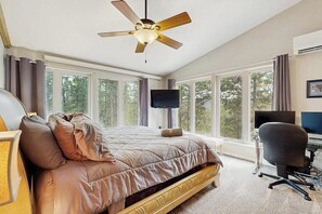 A bedroom with a bed, a desk, a chair, a television, and large windows. - Spacious and secluded home with mountain views, gas grill, decks & home office (Rapid City)