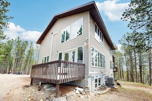 A two-story house with a deck, large windows, and a chimney. - Spacious and secluded home with mountain views, gas grill, decks & home office (Rapid City)
