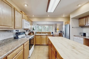 Una cocina moderna con armarios de madera, encimeras de granito y electrodomésticos de acero inoxidable, además de una isla grande.