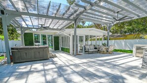 Eine überdachte Terrasse mit Whirlpool, Sitzgelegenheit und einer gläsernen Struktur.