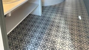 Ein modernes Badezimmer mit Badewanne, Waschbecken und Dusche. Der Boden ist mit einem geometrischen Fliesenspiegel versehen.
