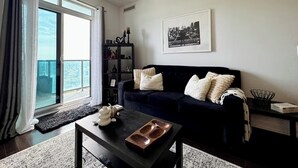A modern living room with a dark blue sofa, a coffee table, and a bookshelf. - Modern Designed Home (Sebright)