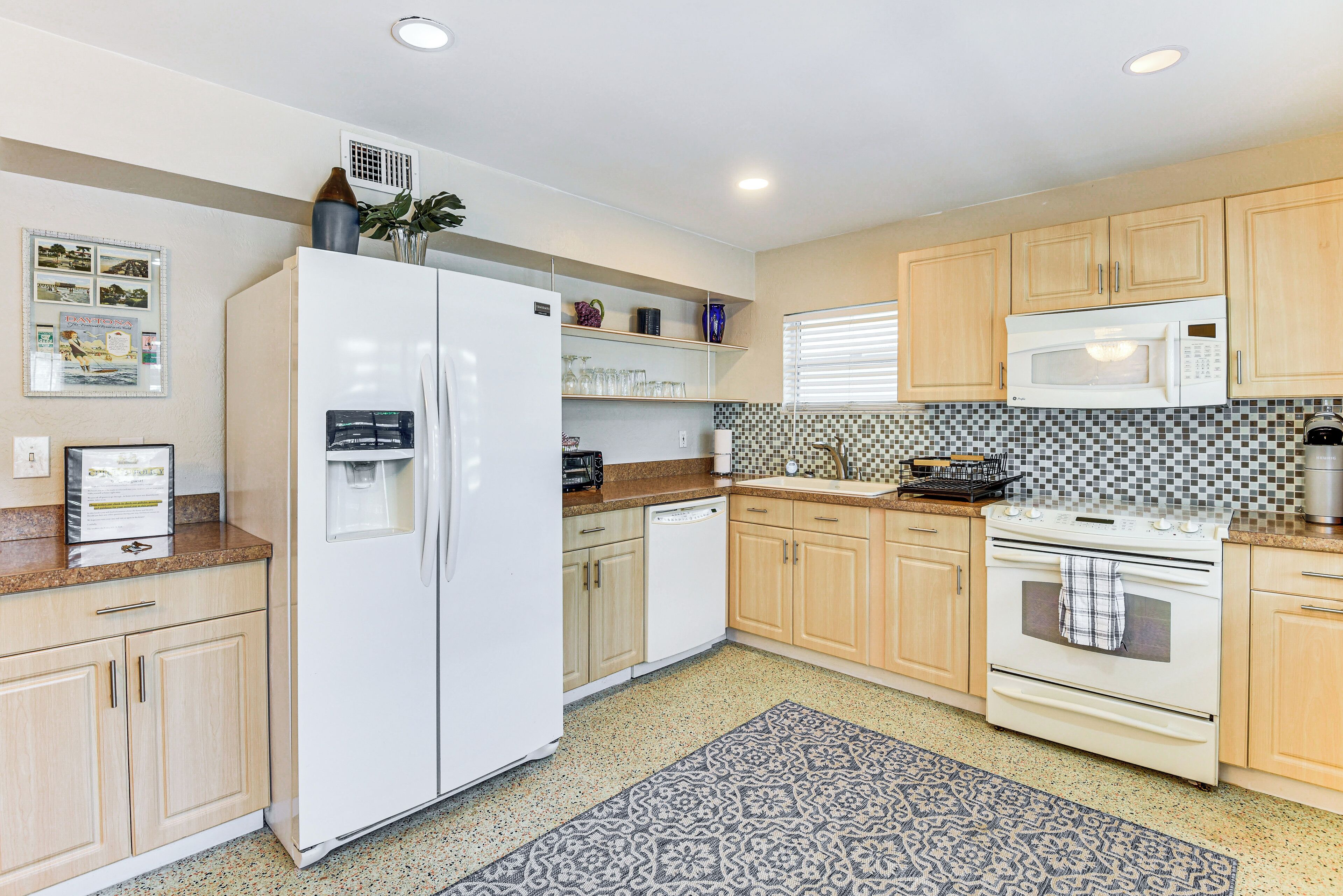 Una cocina con refrigerador, microondas, horno y salpicadero de azulejos.