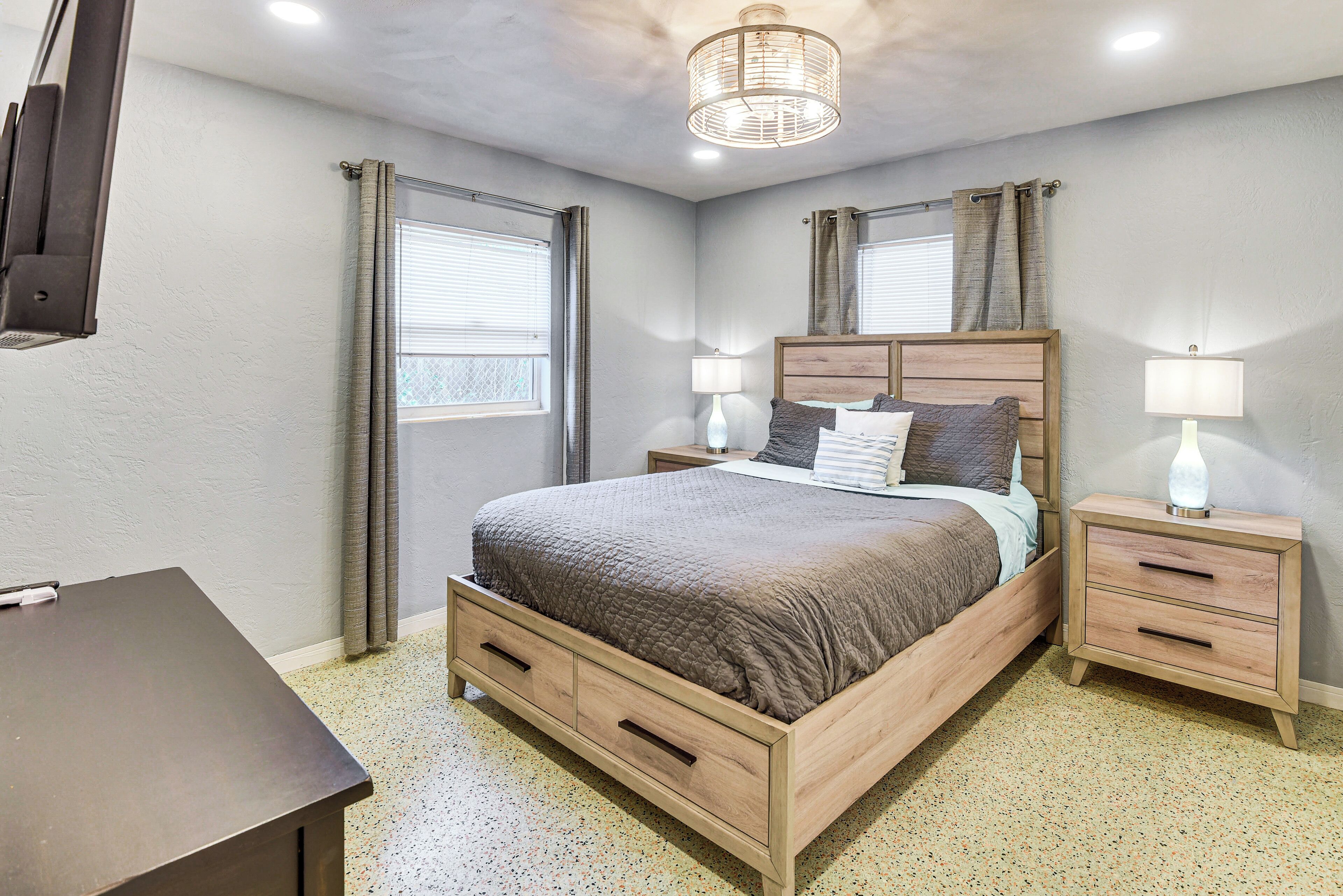 Una camera da letto con un letto di legno, due comodini, una scrivania e una lampada a soffitto.