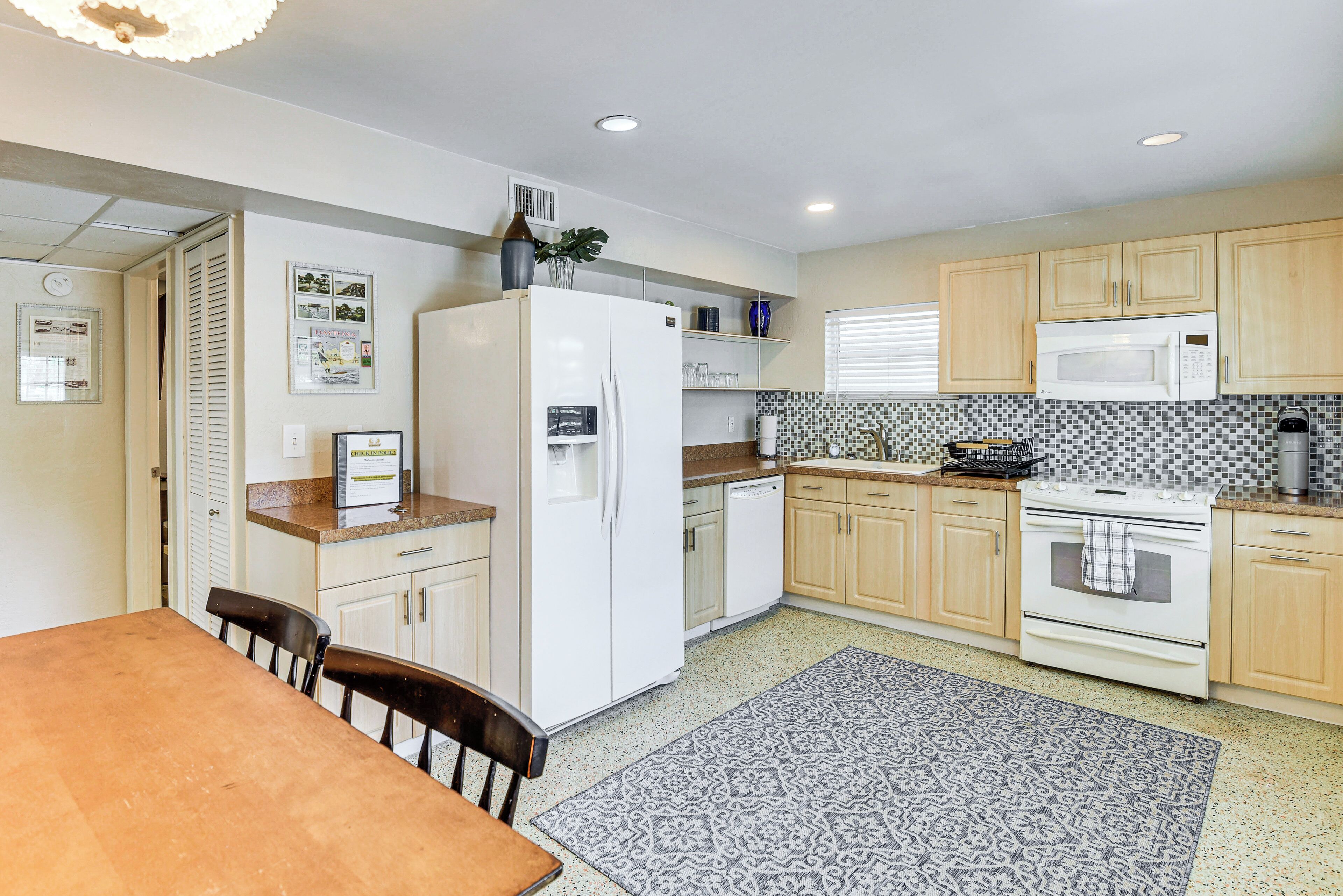 A compact kitchen with a refrigerator, microwave, stove, and a dining area with a table and chairs.