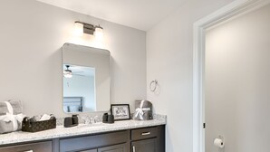 A modern bathroom with dark cabinets, a large mirror, and a countertop with toiletries. - 5 Mi to Auburn University: Sleek Townhome w/ Patio (Opelika)