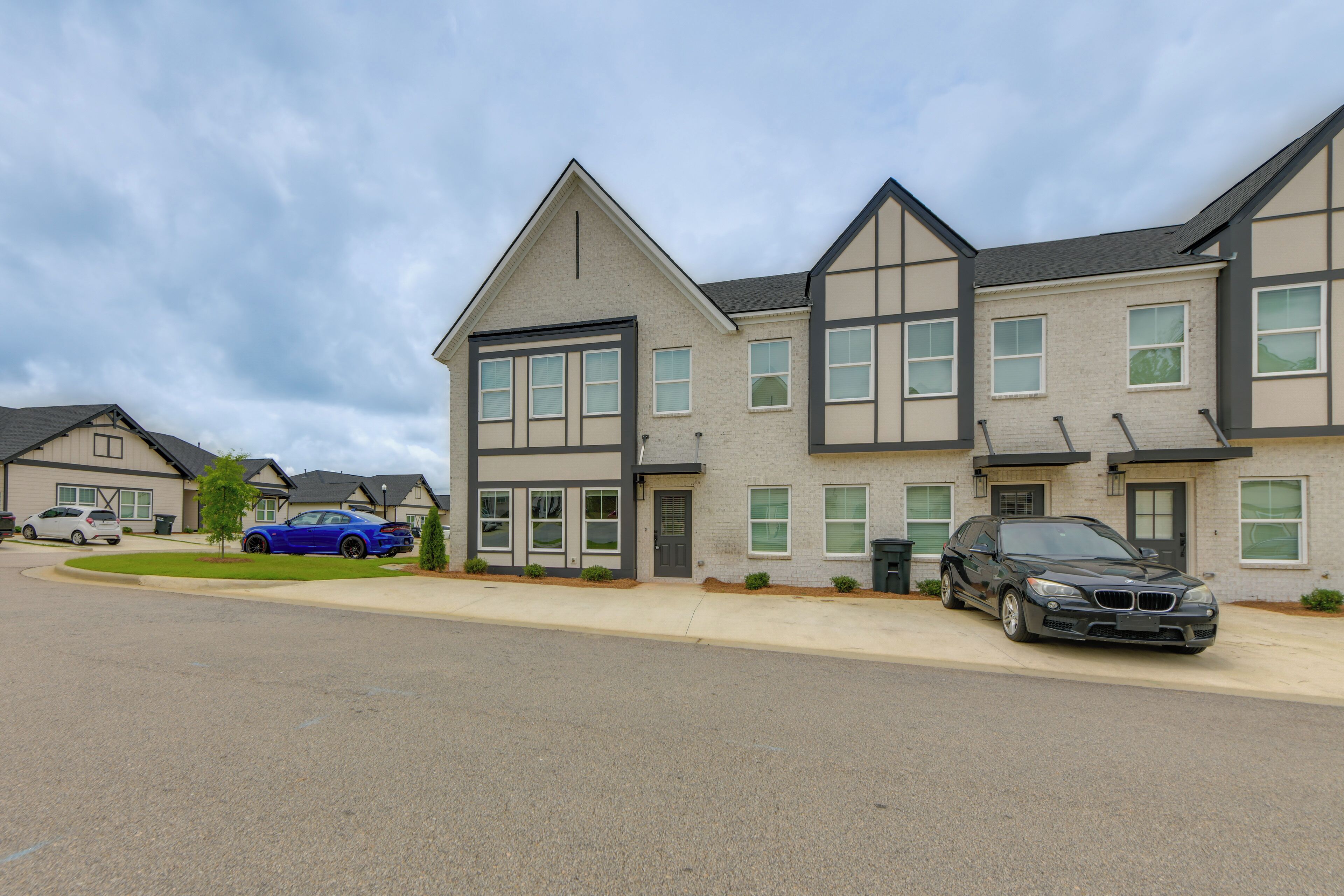 Un quartier résidentiel avec des maisons modernes, une allée et des voitures garées.