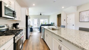 A modern kitchen with white cabinets, granite countertops, stainless steel appliances, and a central island. - 5 Mi to Auburn University: Sleek Townhome w/ Patio (Opelika)