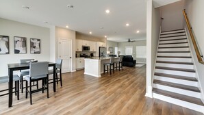 A spacious kitchen with wooden flooring, a dining area with a table and chairs, and a staircase with a wooden handrail. - 5 Mi to Auburn University: Sleek Townhome w/ Patio (Opelika)