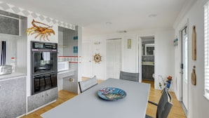 Une cuisine moderne dotée d’un four encastré, d’une table à manger agrémentée d’une assiette décorative et d’une grande décoration murale représentant un homard.