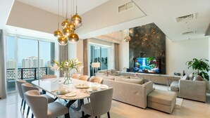 Una sala de estar moderna con comedor, televisor grande y balcón con vistas a la ciudad.