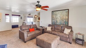 Ein geräumiges Wohnzimmer mit Ledersofas, einem Couchtisch und einem Deckenventilator.