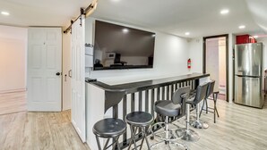 Une cuisine moderne avec un plan de travail noir, un réfrigérateur en acier inoxydable et trois tabourets de bar.