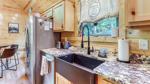 A wooden cabin kitchen with a stainless steel refrigerator, granite countertops, and a sink. - 10 Mi to Main St Murphy: Cabin w/ Covered Deck! (Murphy)