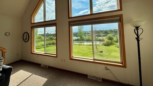 A room with large windows offering a view of a lake and greenery. - Relax at Bear Hug House on Bear Lake Manawa Wi.– Private Pond & Easy Lake Access (Manawa)