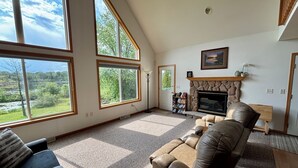 A spacious living room with large windows, a fireplace, and a comfortable seating area. - Relax at Bear Hug House on Bear Lake Manawa Wi.– Private Pond & Easy Lake Access (Manawa)