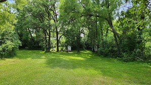 A grassy outdoor area with picnic tables and a small shed.