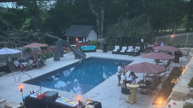 Un área de piscina con sillas de descanso, una mesa con comida y un tobogán.