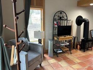 A living room with a sofa, a TV on a stand, a coat rack, and a window with curtains.