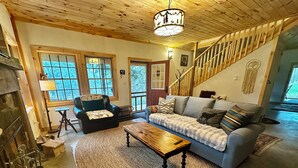 A cozy living room with a fireplace, a sofa, a coffee table, and a staircase leading to another level.