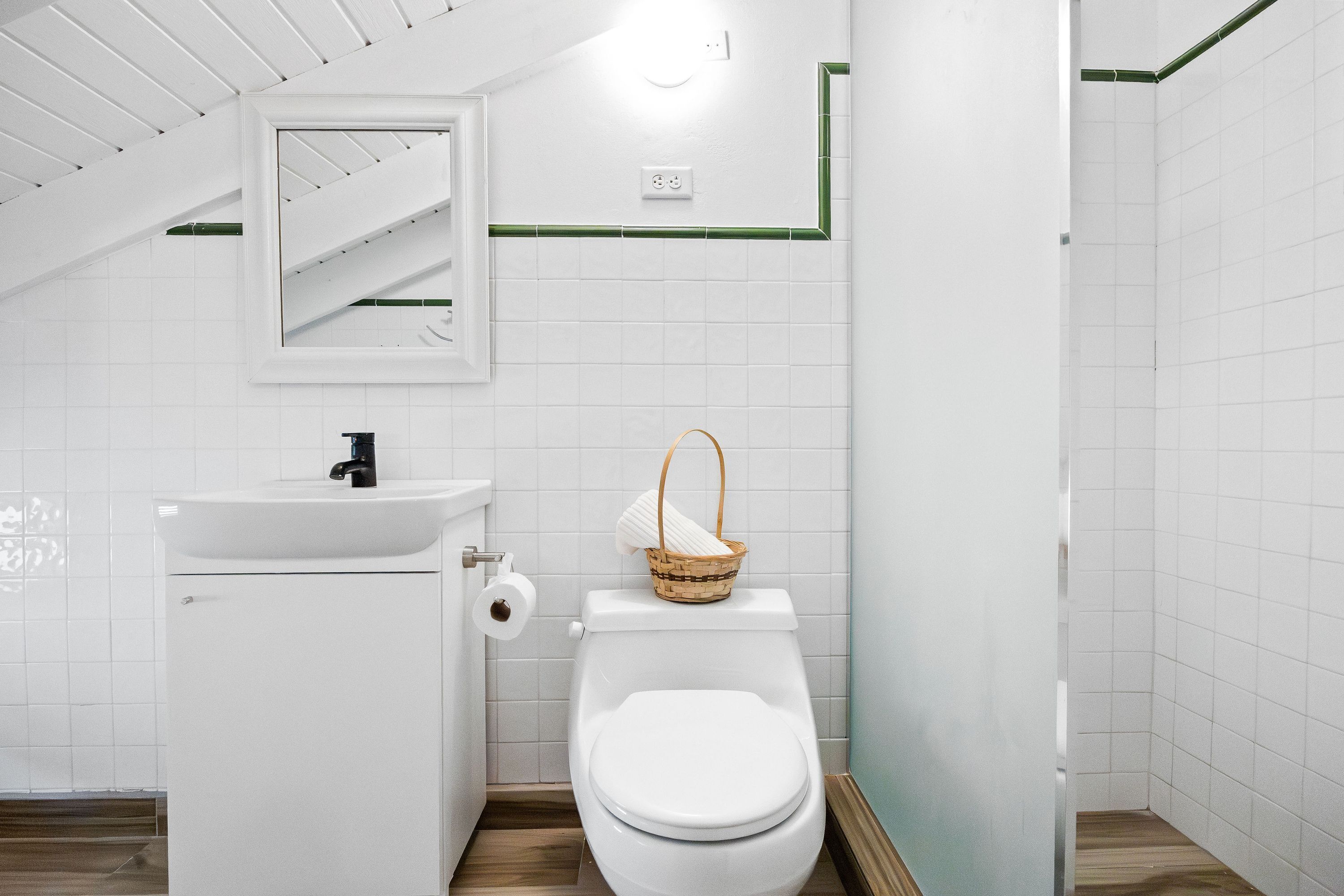 A bathroom with a white toilet, a sink, and a mirror.