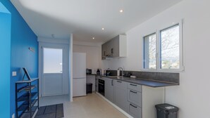 Een moderne keuken met grijze kastjes, een zwarte prullenbak en een raam met uitzicht.