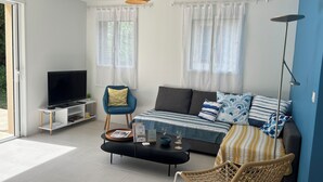 Een moderne woonkamer met een bank, een televisie, een salontafel en een fauteuil.